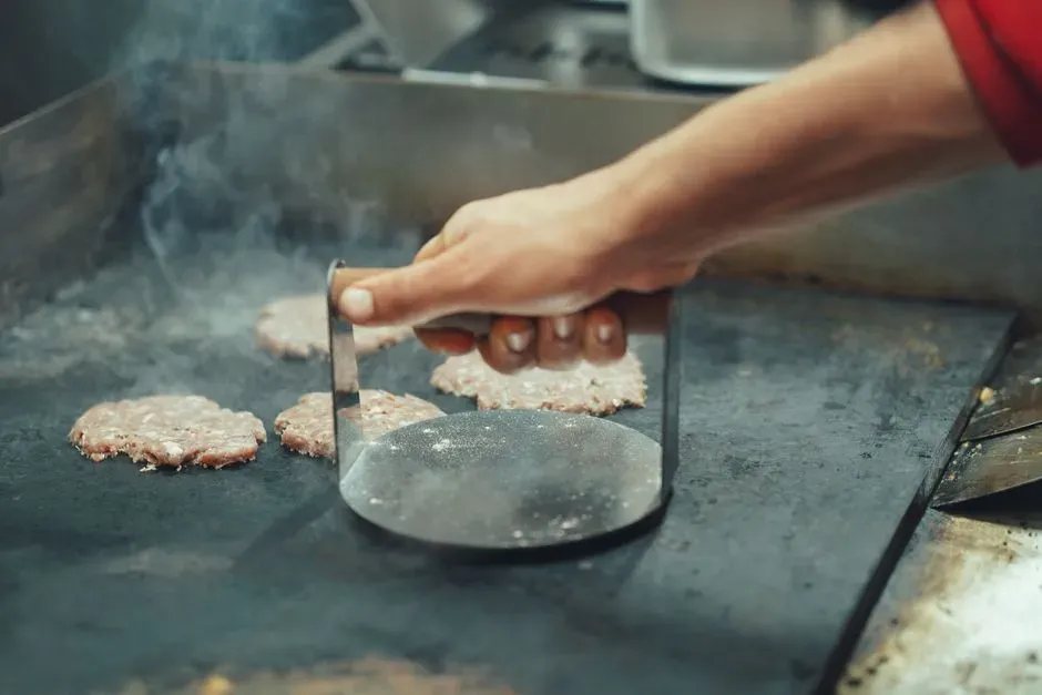 4. Pressing down on the patty with a spatula (Image Credits: Pexels)