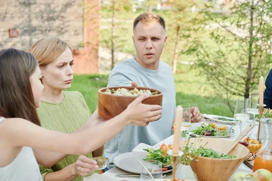 Passing dishes instead of reaching across the table (Image Credits: Pexels)