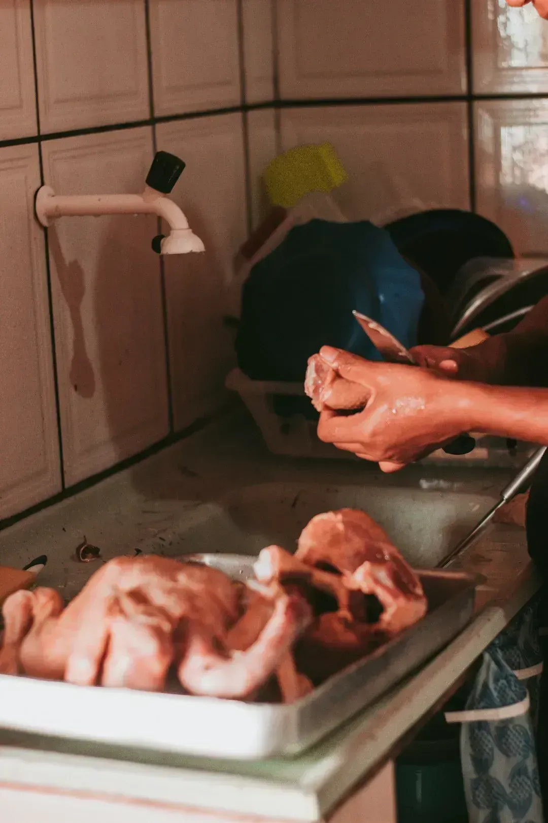 1. Rinsing raw chicken under the tap (Image Credits: Unsplash)