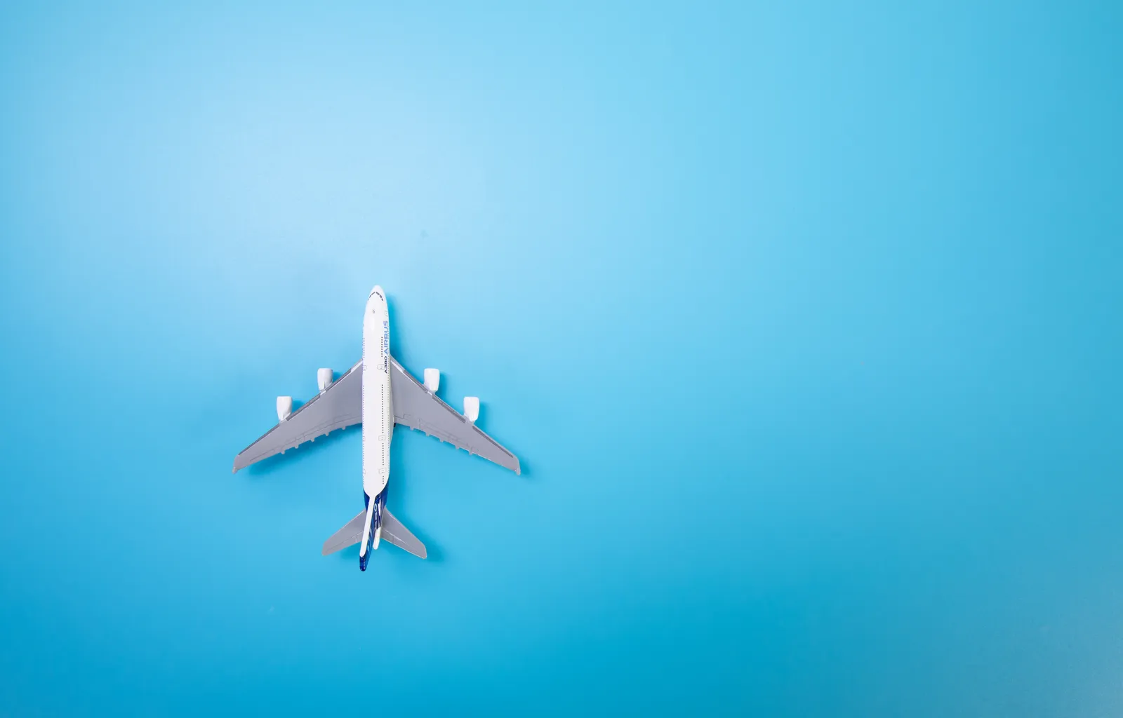 How Far in Advance You Book Matters More Than the Day (Miniature white airplane on a blue background. Horizontal photo, banner, flat lay. Space for text, copy space. Concept - air travel, ticket booking, CC BY 2.0)